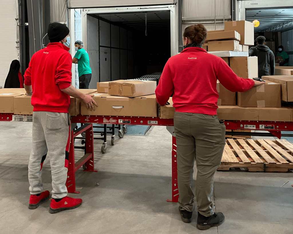 two people on a conveyor line demonstrate the order fulfillment process