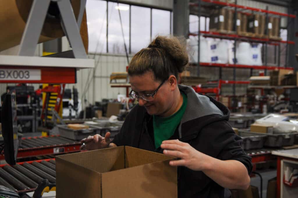 Worker at a direct fulfillment center packs a box